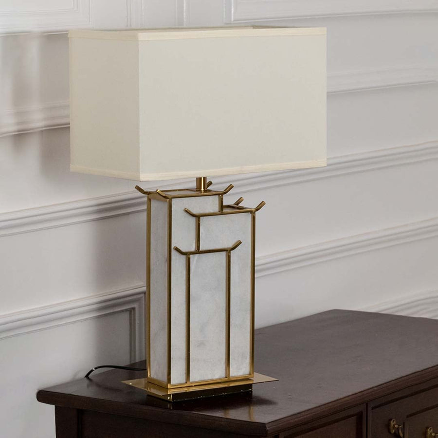 White rectangular shade marble and gold geometric table lamp on wooden sideboard with light off for elegant modern décor.
