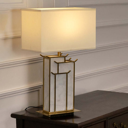 Gold metal table lamp with geometric frame and fabric shade creating sophisticated modern ambient lighting indoors.