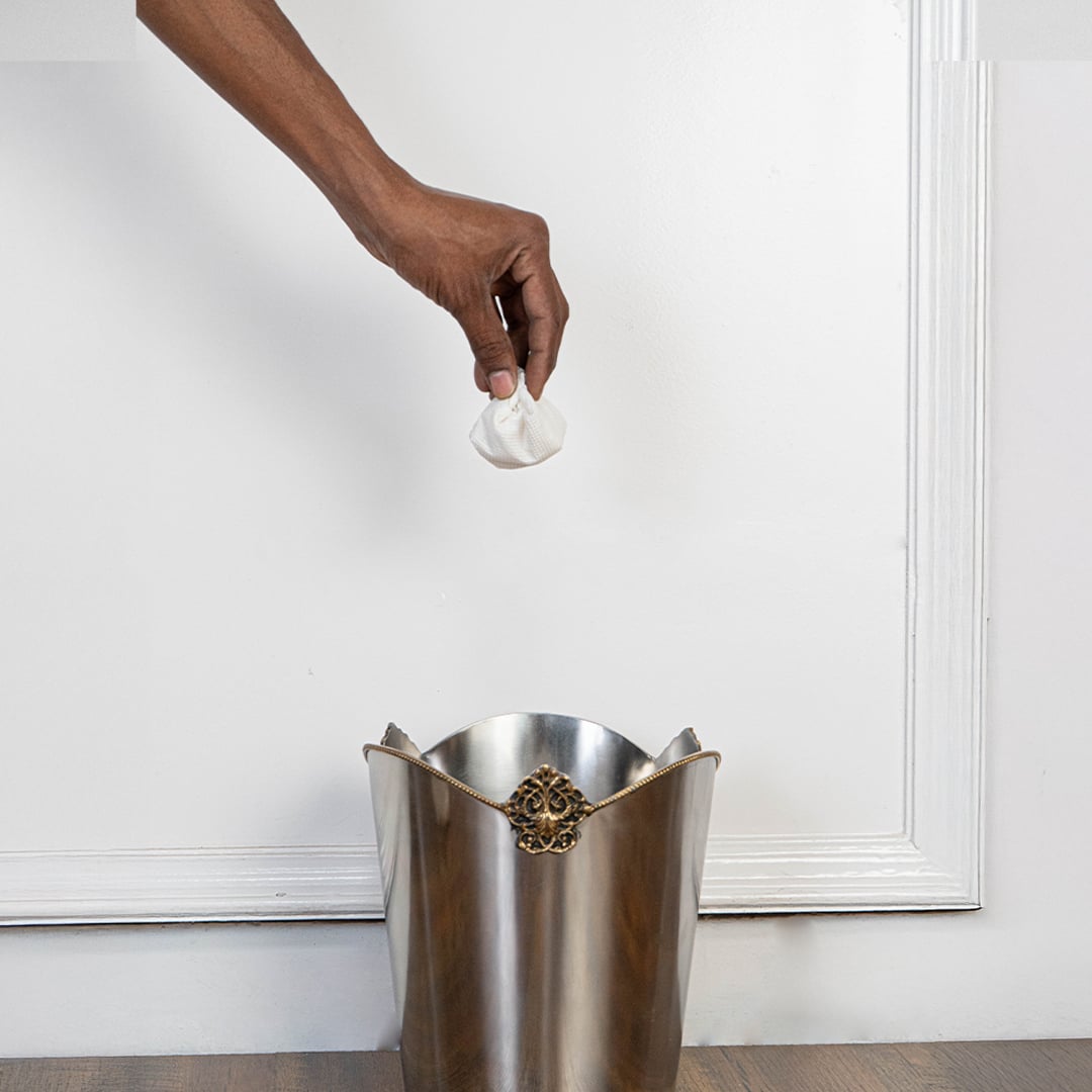 Stainless steel trash bin with gold floral crest and scalloped edge displayed on plain white background front view.