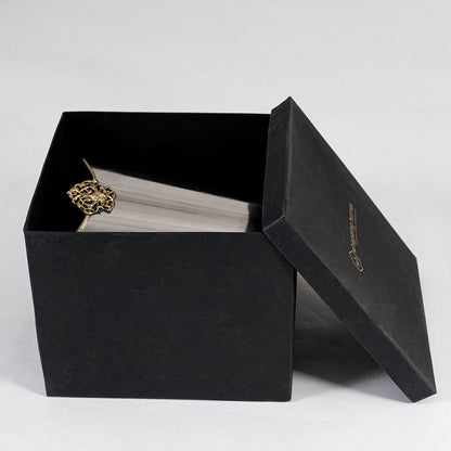 Silver waste bin with gold detail partially packed in black branded box with open lid for elegant gift-ready display.