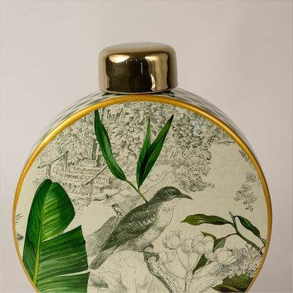 Closeup of tropical bird jar highlighting hand-drawn bird design  lush green leaves  and glossy gold finish.