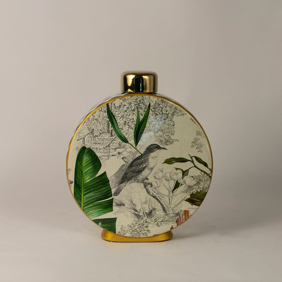 Tropical bird jar with golden detailing and botanical print featuring bird and tropical leaves on white background.