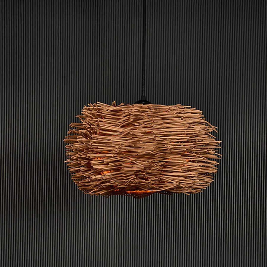 Rattan twig pendant light on black background highlighting its intricate natural weave and organic handcrafted texture.