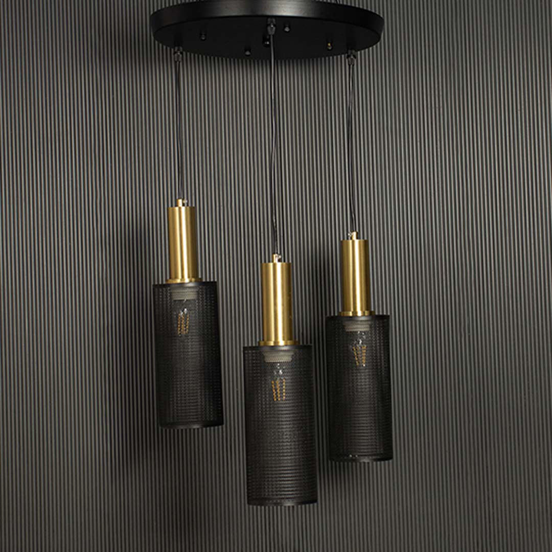 Triple mesh pendant light with gold accents and black perforated shades shown against a black background emphasizing its geometric form.