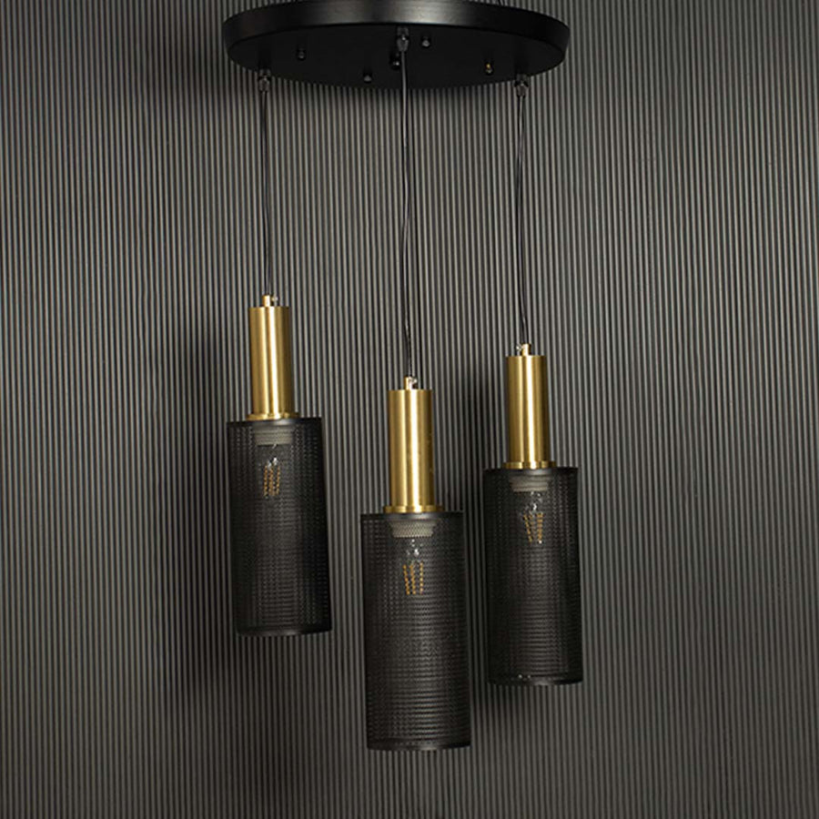 Triple mesh pendant light with gold accents and black perforated shades shown against a black background emphasizing its geometric form.