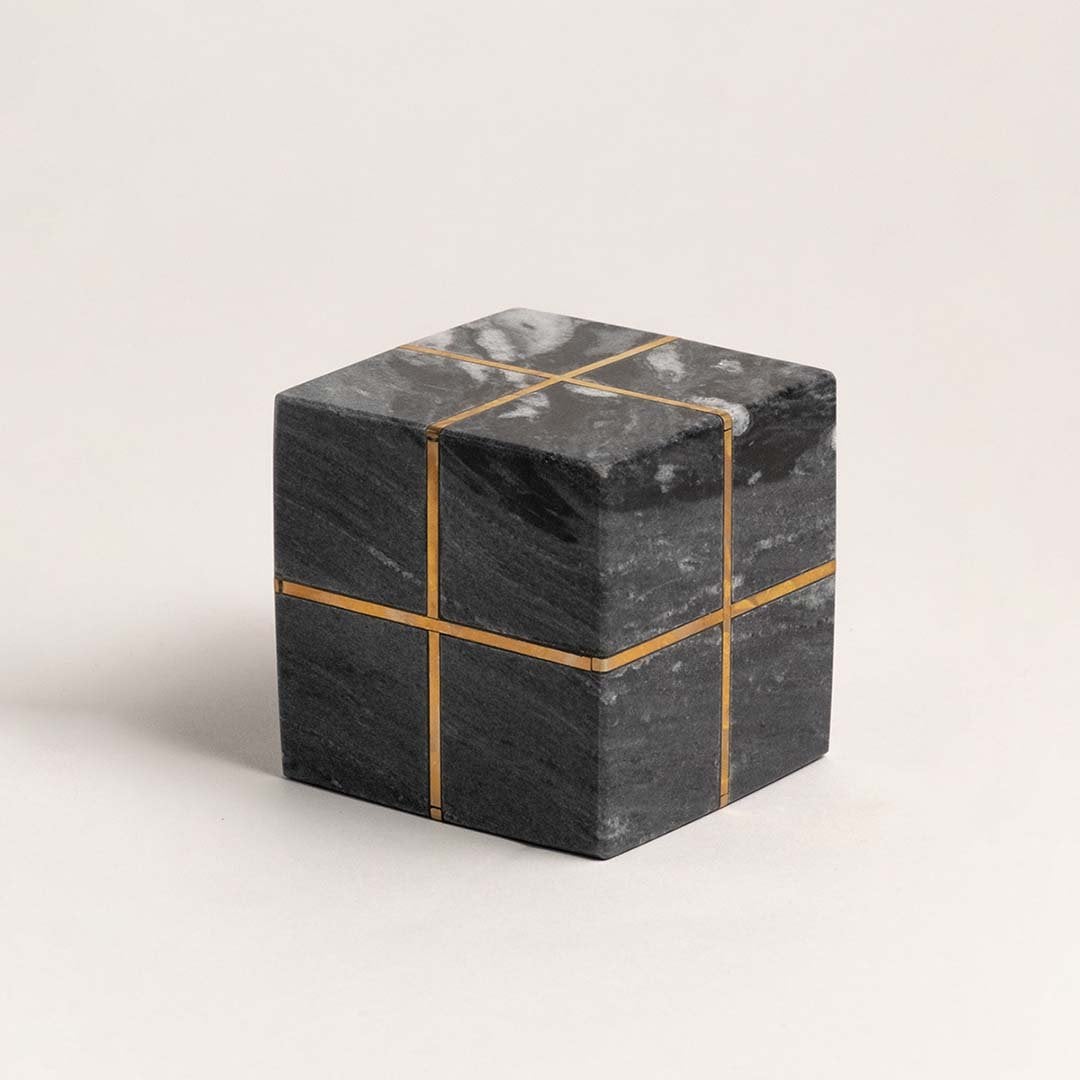 Minimalist black marble cube with gold inlays displayed on a clean white background emphasizing design details.