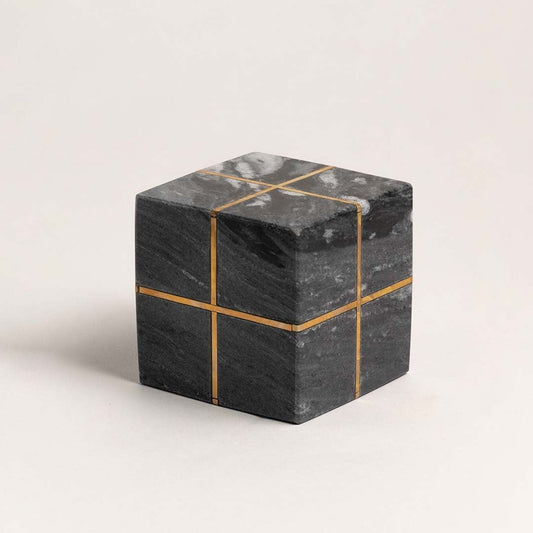 Minimalist black marble cube with gold inlays displayed on a clean white background emphasizing design details.