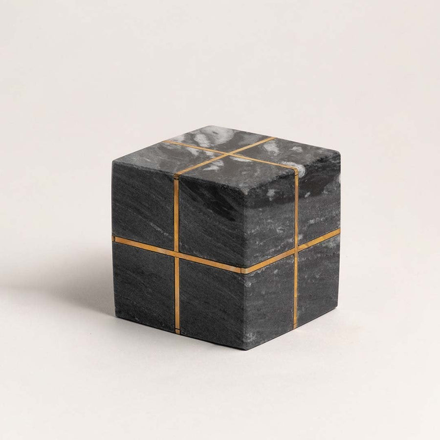 Minimalist black marble cube with gold inlays displayed on a clean white background emphasizing design details.