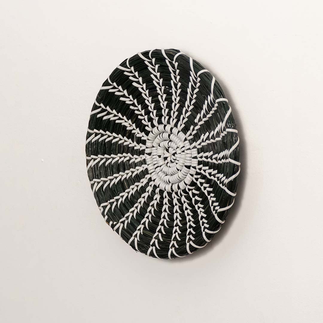 Side profile of the flat woven wall basket showing the natural fiber texture and thin rim design on a white surface for quality.