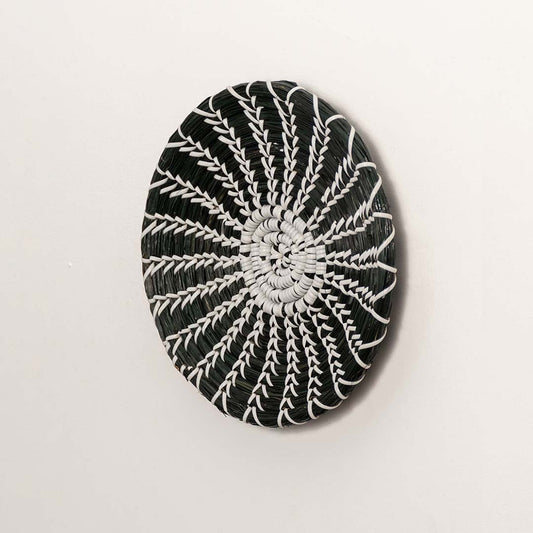 Side profile of the flat woven wall basket showing the natural fiber texture and thin rim design on a white surface for quality.