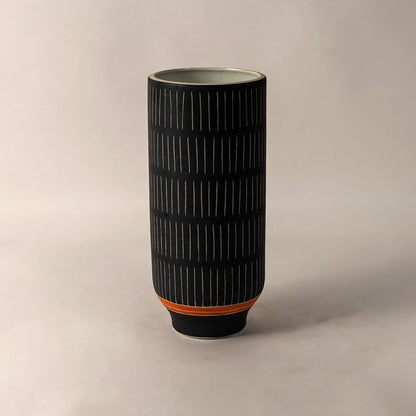 Contemporary black ceramic striped vase with orange detail styled for home interior decoration on simple white background.
