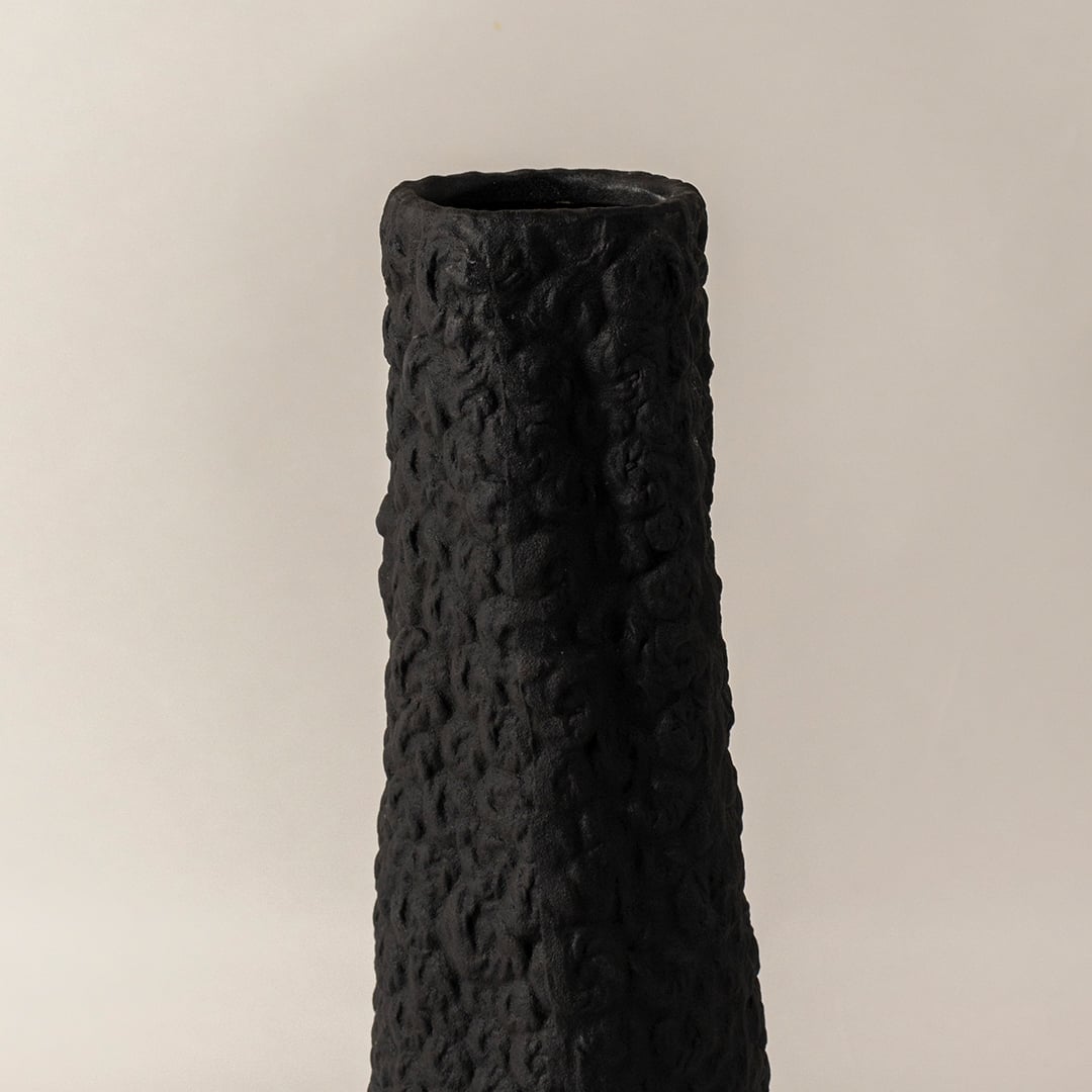 Closeup of black ceramic vase with handcrafted textured surface highlighting artistic detail perfect for home decoration.