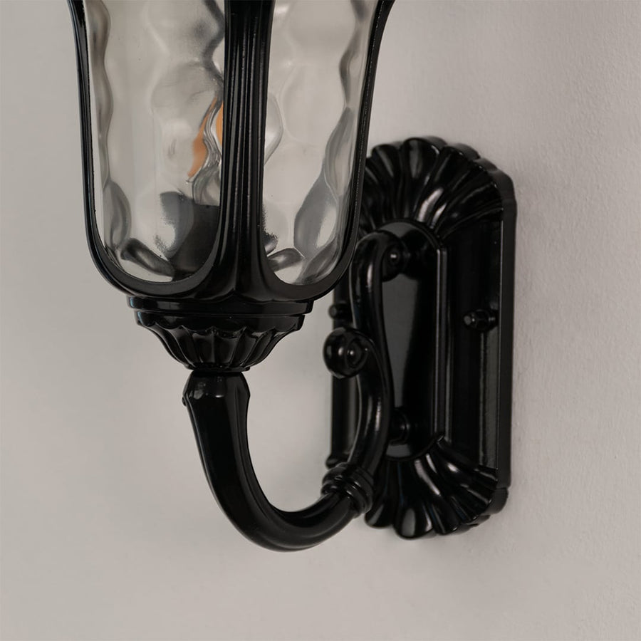 Close detailed view of black outdoor wall lantern highlighting textured glass classic curved arm and premium outdoor finish.