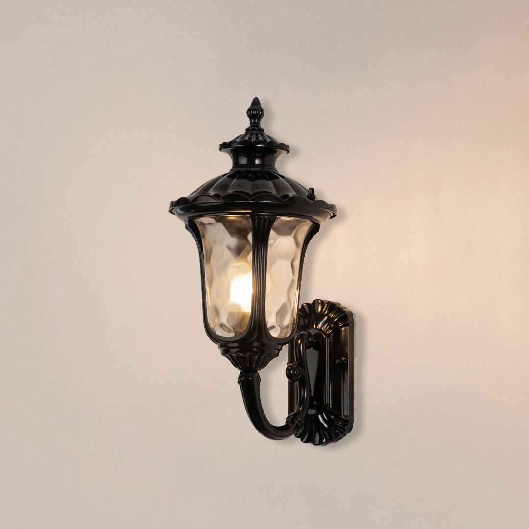 Black metal outdoor lantern wall light on white background with warm glow for classic exterior decor.