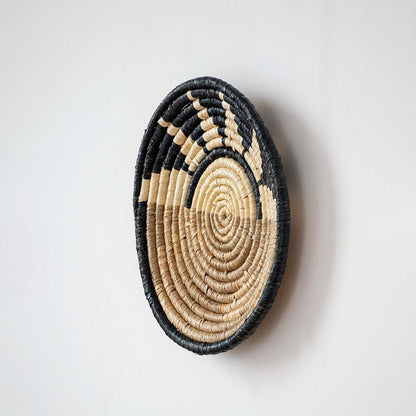 Side profile of handwoven bamboo wall plate in black beige showing texture depth and detailed woven craftsmanship.