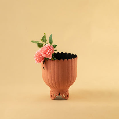 Matte terracotta ribbed metal planter with pink flowers for warm modern home decor and artistic accents.