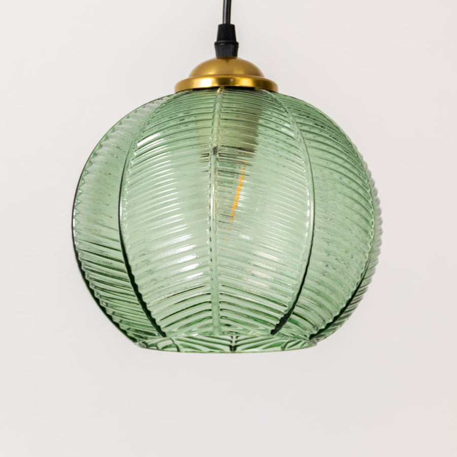 Detailed view of green ribbed glass and gold metal pendant light highlighting textured craftsmanship.