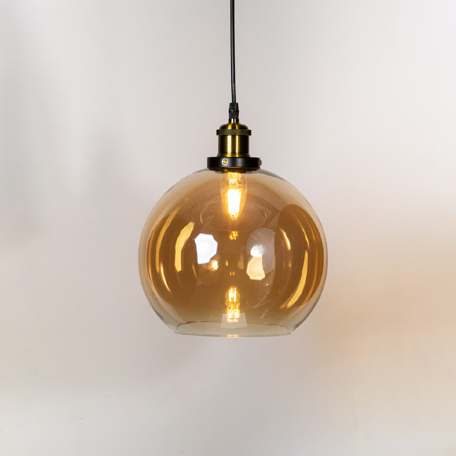 Amber glass globe pendant light with brass metal holder and contemporary design for elegant ceiling lighting decor.
