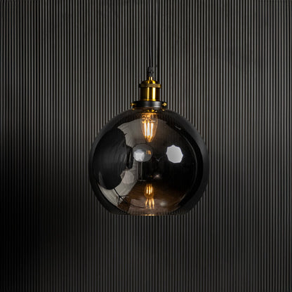 Glass globe pendant light switched on against black background is a stylish modern ceiling hanging light.
