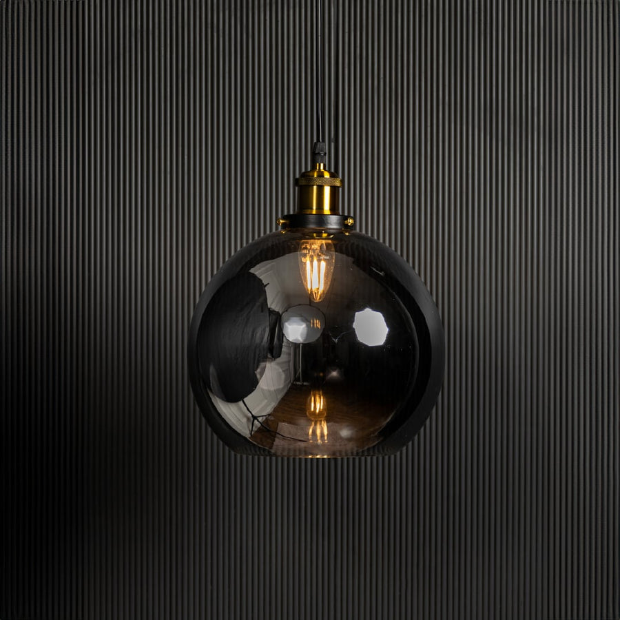 Glass globe pendant light switched on against black background is a stylish modern ceiling hanging light.