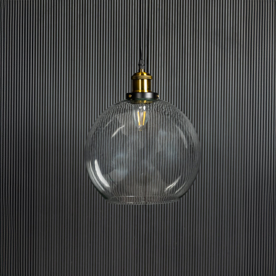 Clear glass globe pendant light with brass accents adding elegance to dining room ceilings.