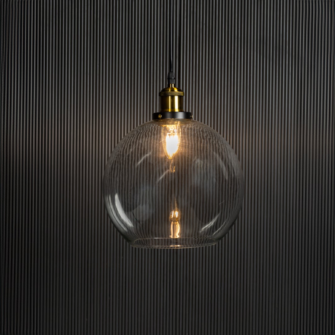 Clear glass globe pendant light illuminated with warm glow creating inviting interior ambience.