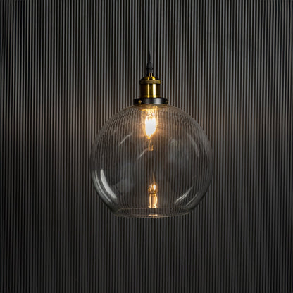 Clear glass globe pendant light illuminated with warm glow creating inviting interior ambience.