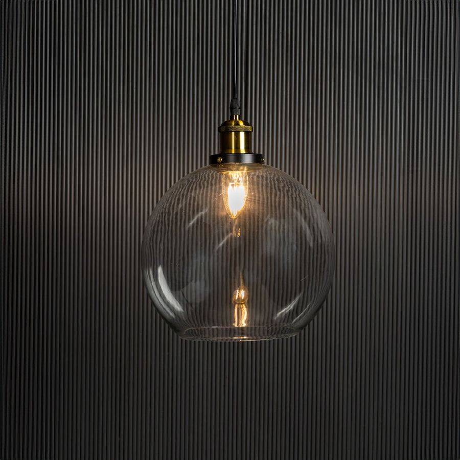 Clear glass globe pendant light illuminated with warm glow creating inviting interior ambience.