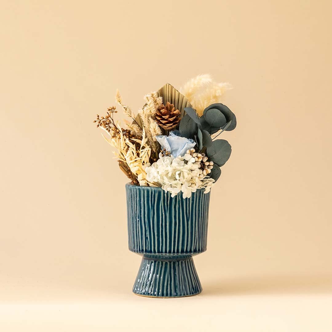Blue textured pedestal vase displayed on a clean white background highlighting its vertical stripe pattern and contemporary sculptural shape.