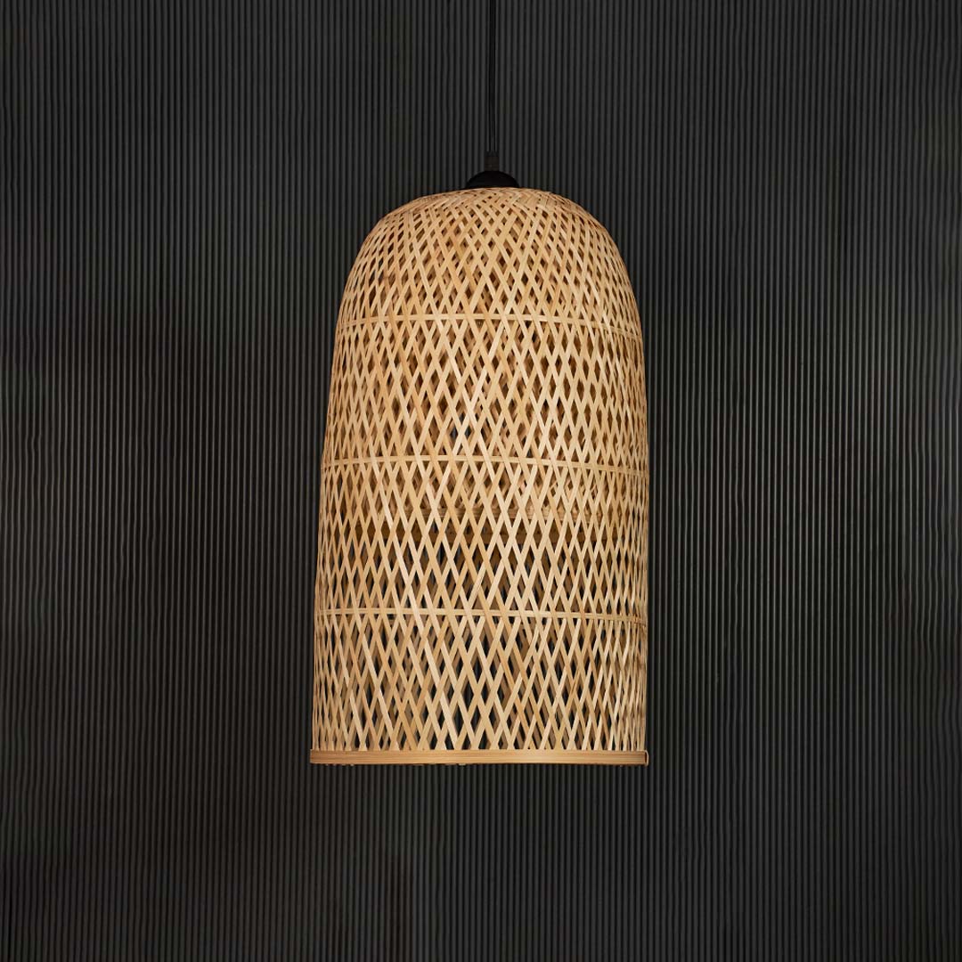 Rattan pendant light with tall cylindrical bamboo shade in natural handwoven finish turned off on black background.