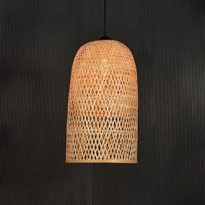 Tall rattan pendant light with woven bamboo cylindrical shade turned on glowing softly against black background.