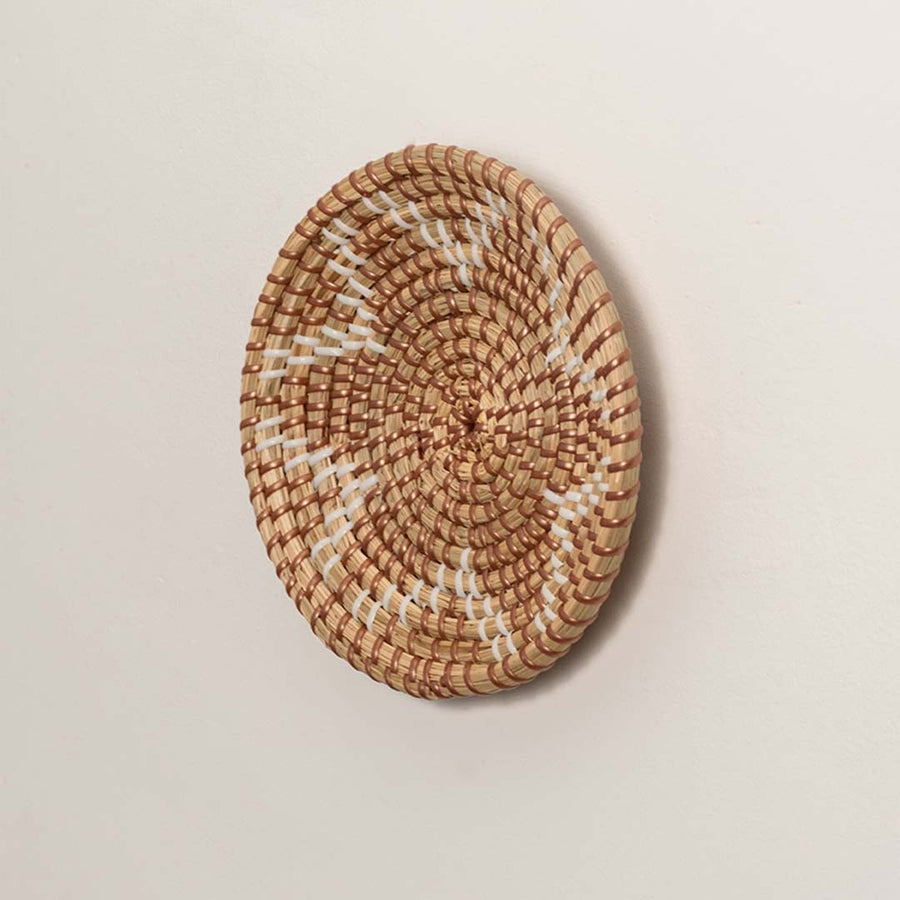 Side profile of the flat woven wall basket showing the natural texture and thin rim design on a white surface for craftsmanship detail.ng Seagrass Woven Wall Basket Side View