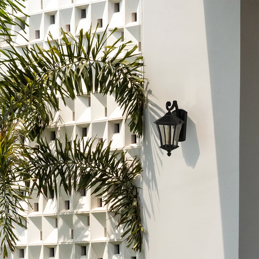 Black metal vintage outdoor wall lantern with patterned glass mounted on a modern white exterior wall creating an elegant architectural lifestyle ambience.