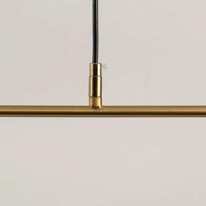 Closeup of gold linear pendant light showing curved metal frame white diffuser tube and refined modern craftsmanship.