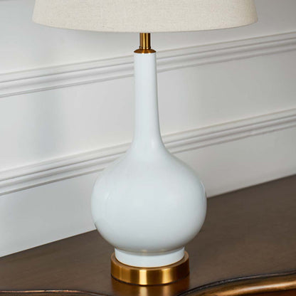 Closeup of ceramic lamp body with glossy white finish and gold detailing showing fine craftsmanship and smooth sculpted curves.