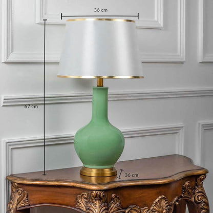 Green ceramic table lamp with fabric shade and golden base shown with 67cm height and 36cm width.