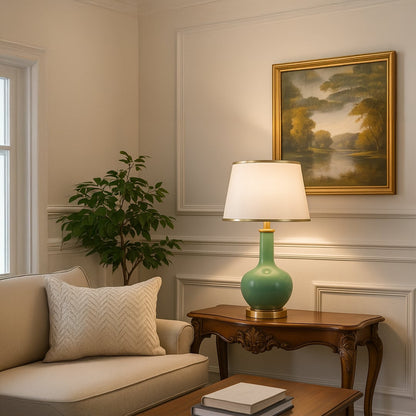 Green ceramic table lamp with golden base and tapered fabric shade adding elegant lighting to living room decor.