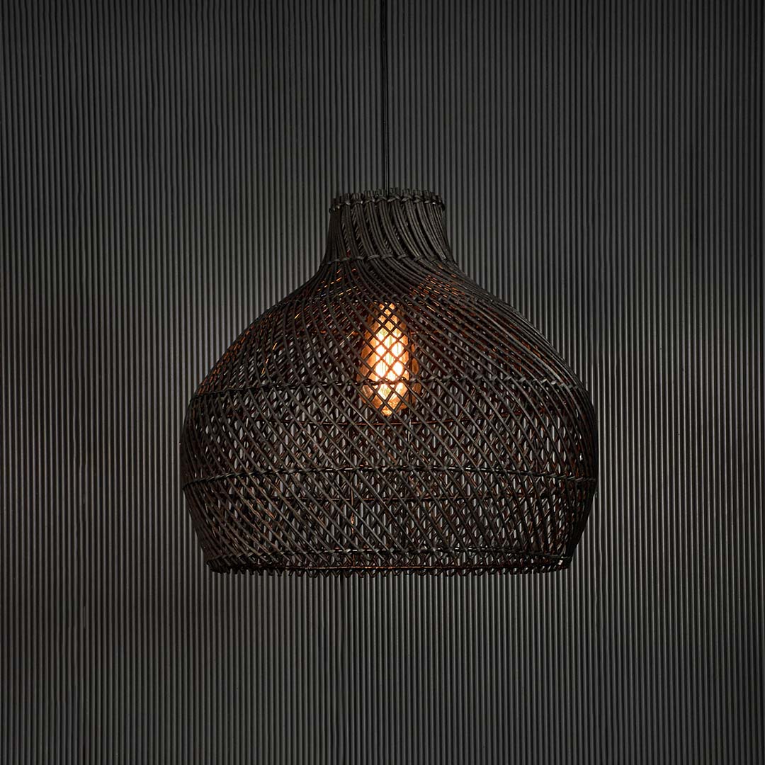 Black rattan pendant light glowing softly on dark background creating cozy ambience with elegant handcrafted design.