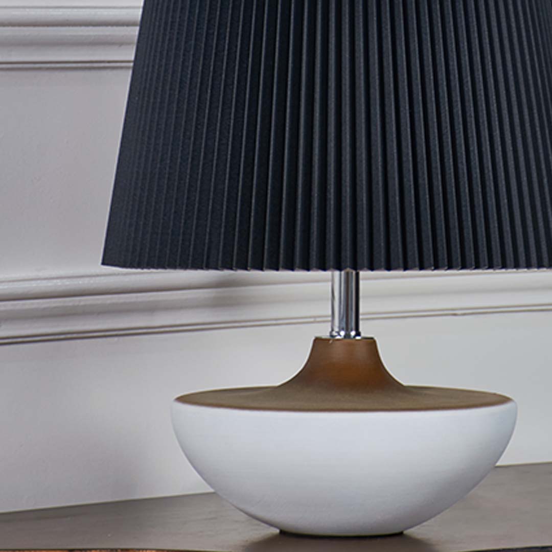 Closeup of black pleated table lamp shade showing detailed texture and golden neck accent for luxury appeal.