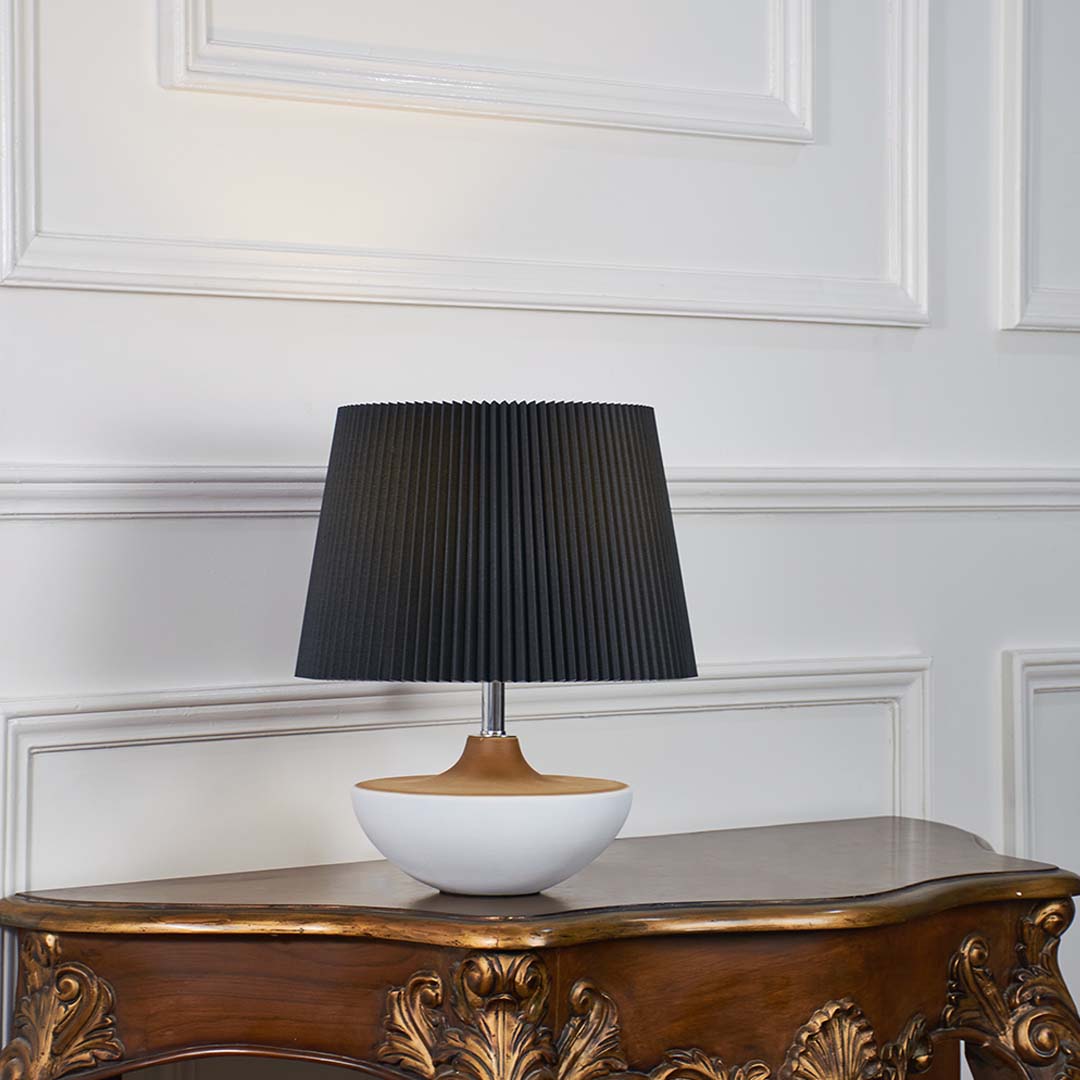 Black fabric shade table lamp with white ceramic base and gold accent designed for elegant bedside and console decor.
