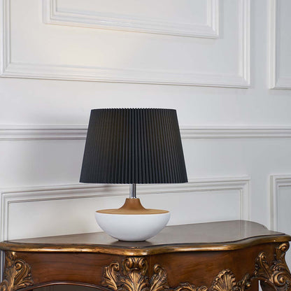 Black fabric shade table lamp with white ceramic base and gold accent designed for elegant bedside and console decor.