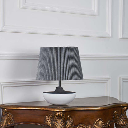 Black and white ceramic lamp with grey pleated shade displayed unlit on a white background showcasing its minimal modern design for clean decor setups.