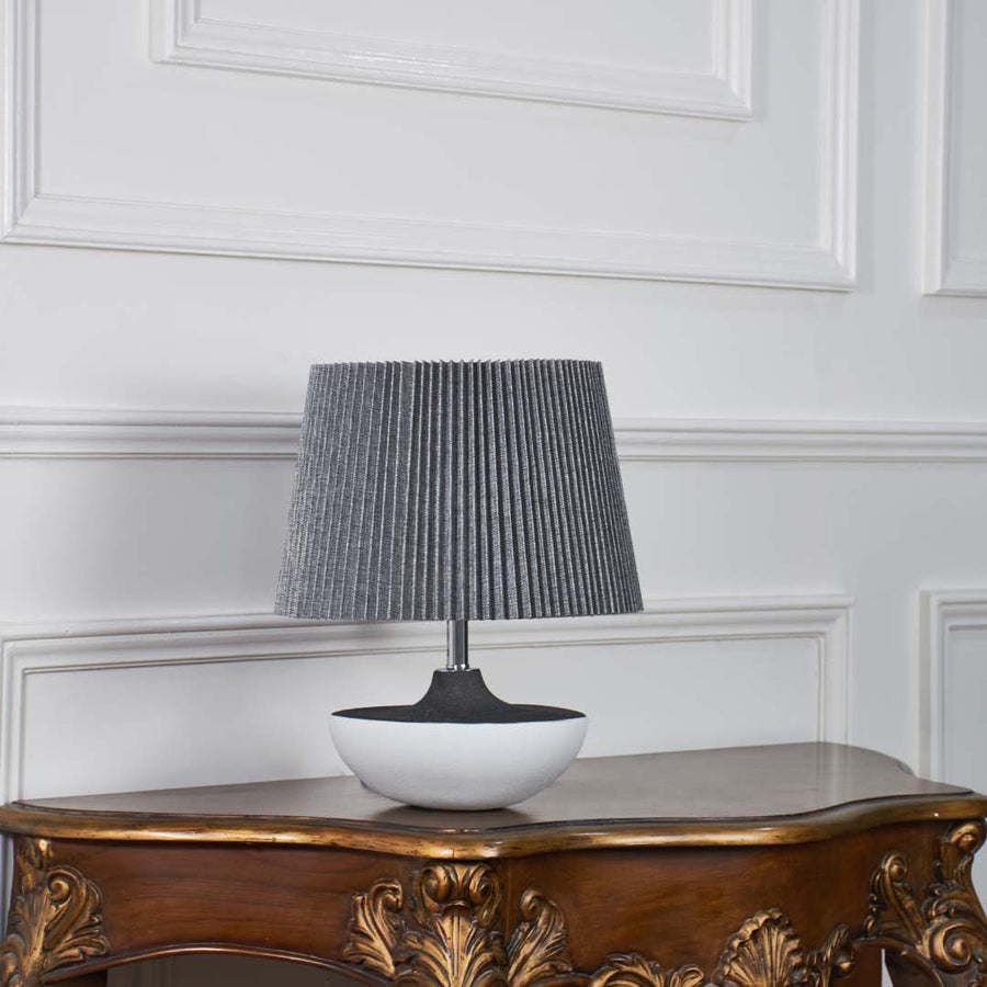 Black and white ceramic lamp with grey pleated shade displayed unlit on a white background showcasing its minimal modern design for clean decor setups.