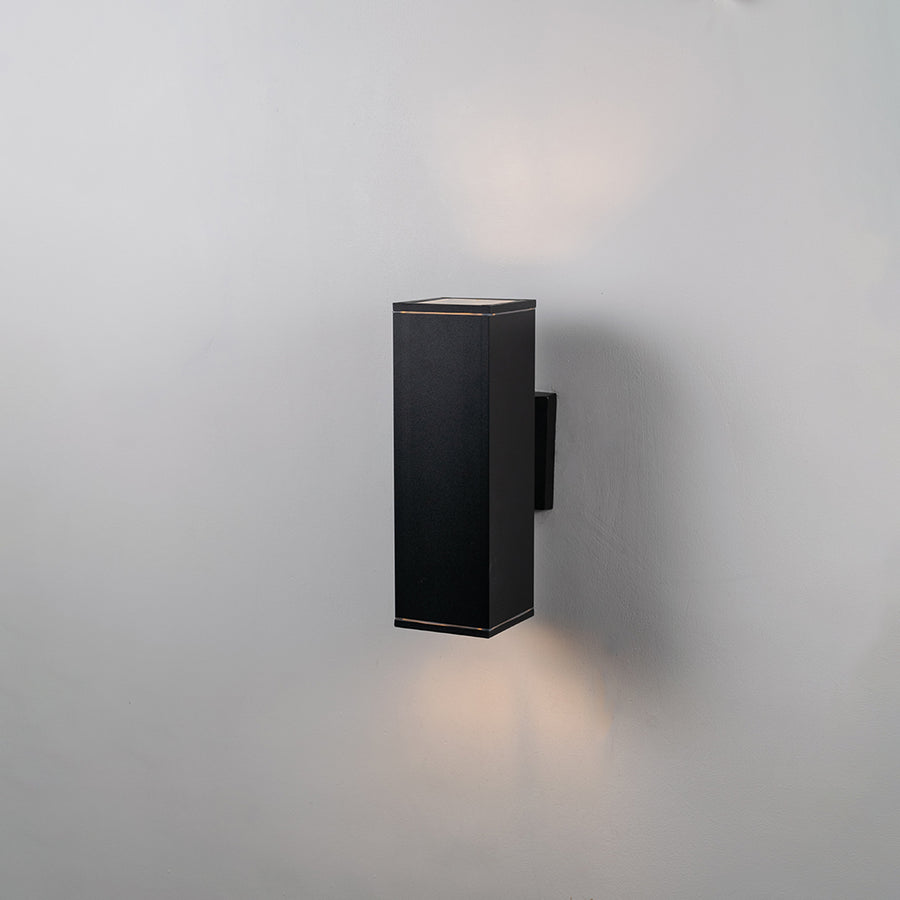 Black metal outdoor wall light on white background with soft downward glow for minimalist exterior decor.