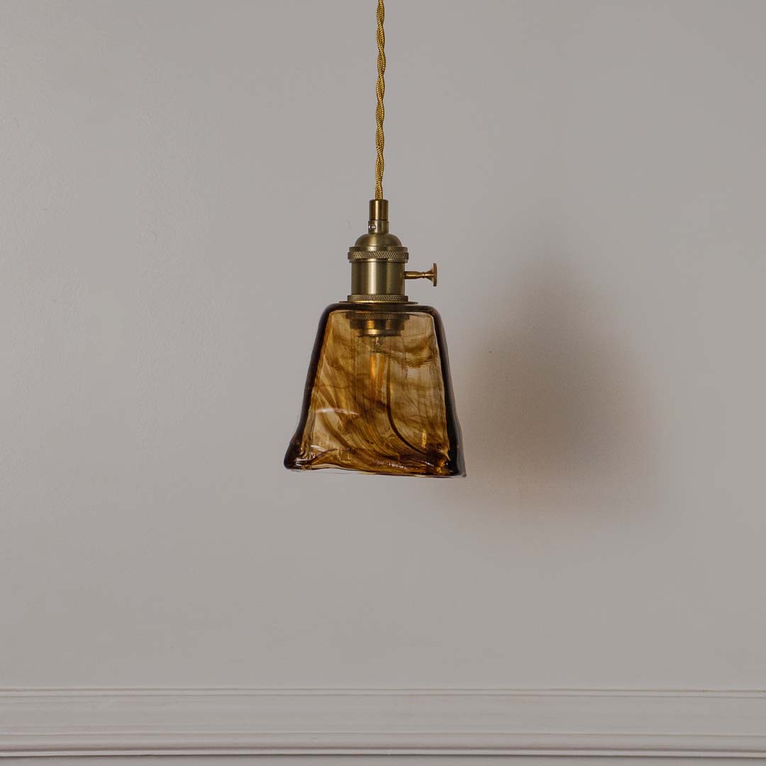 Amber marbled glass pendant light with antique brass fittings crafted for elegant contemporary interiors.