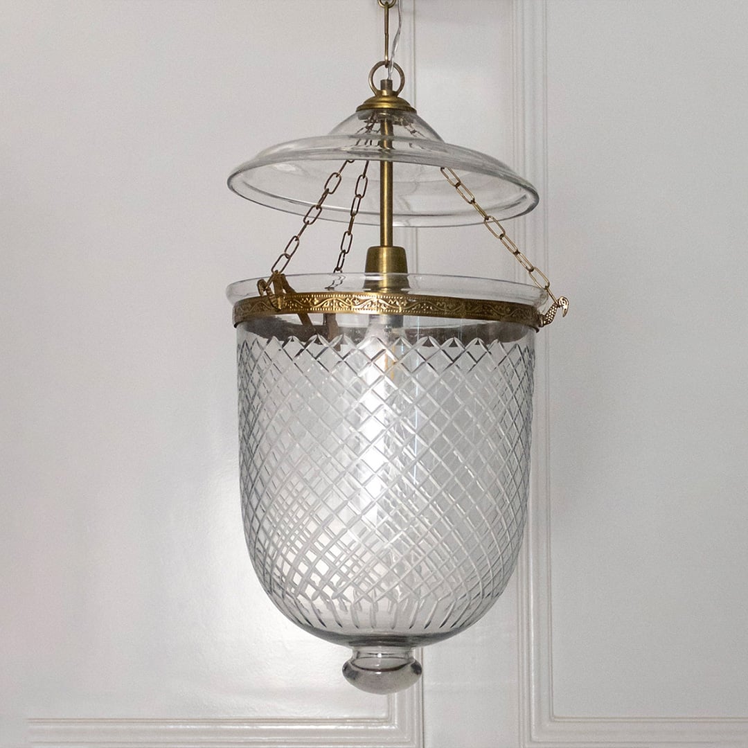 Pendant light featuring antique metal framework and clear textured glass shade suspended elegantly for indoor decor.