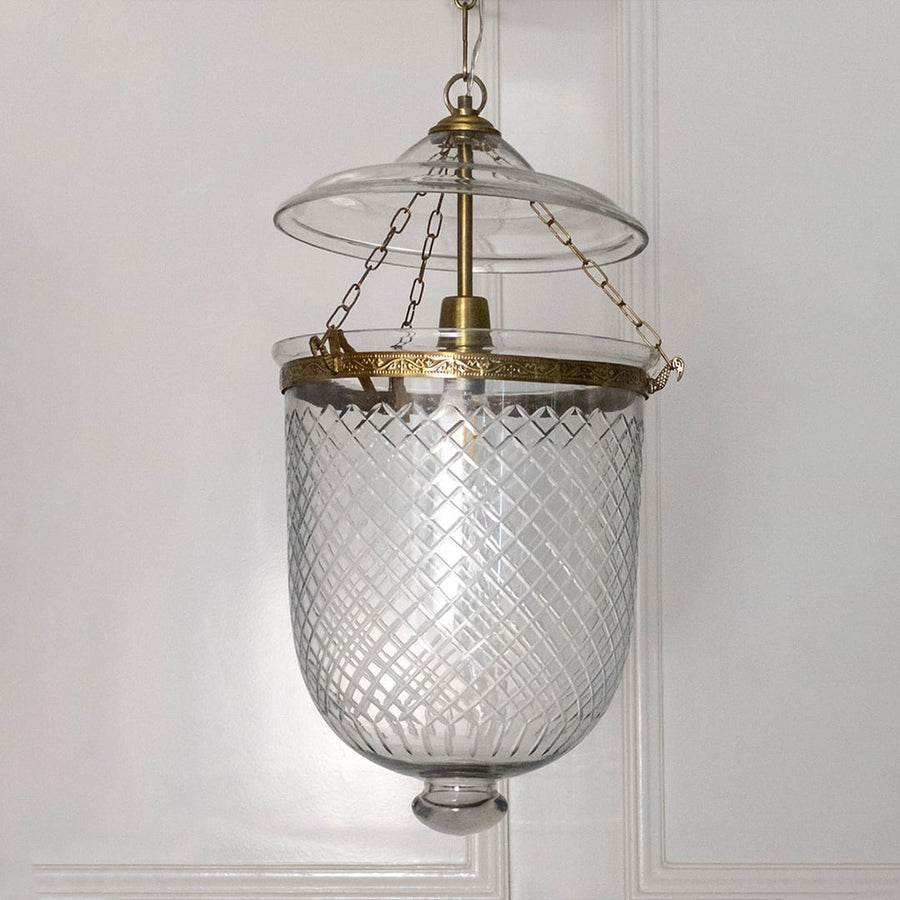 Pendant light featuring antique metal framework and clear textured glass shade suspended elegantly for indoor decor.