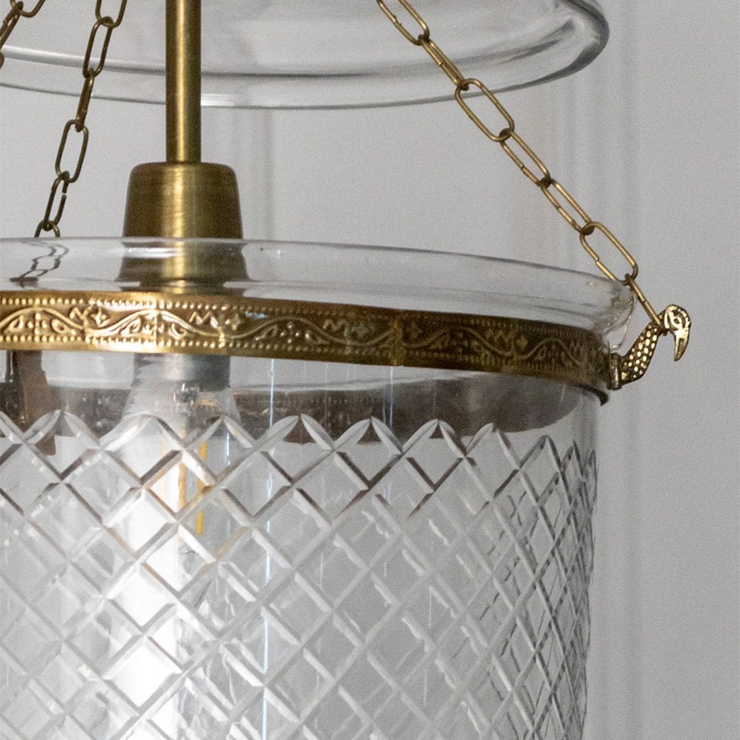 Closeup of antique metal pendant light with textured glass shade showcasing detailed craftsmanship and premium finish.