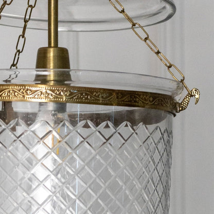 Closeup of antique metal pendant light with textured glass shade showcasing detailed craftsmanship and premium finish.