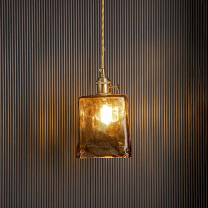 Amber glass pendant light glowing warmly on black background perfect for kitchen dining and modern home interiors.